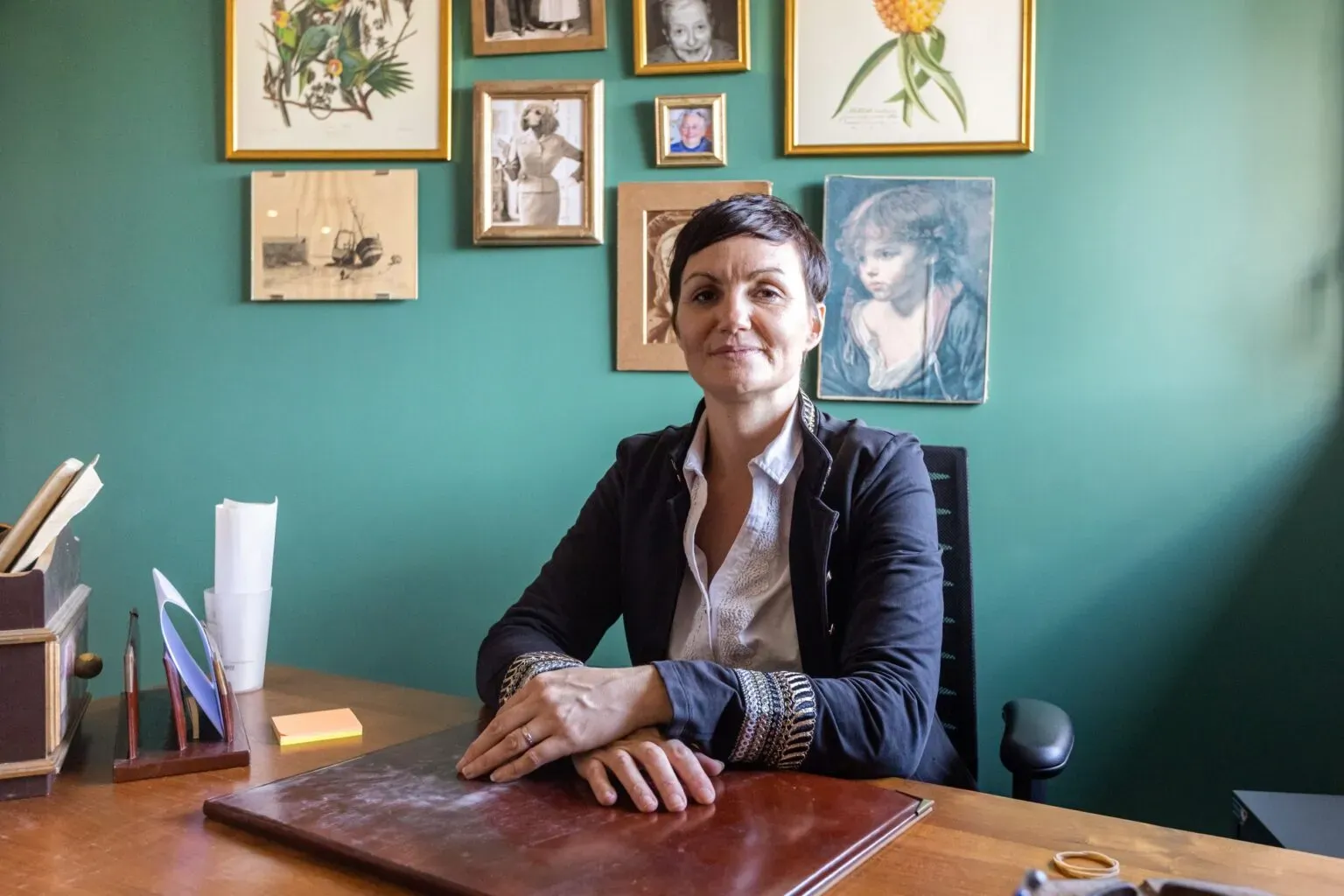 Portrait d’Angélique souriante derrière son bureau en bois.